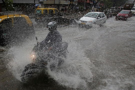 Indians ride through a waterlogged street during monsoon rains in Mumbai, India, Monday, July 1, 2019. India's monsoon season runs from June to September. (AP Photo/Rafiq Maqbool)