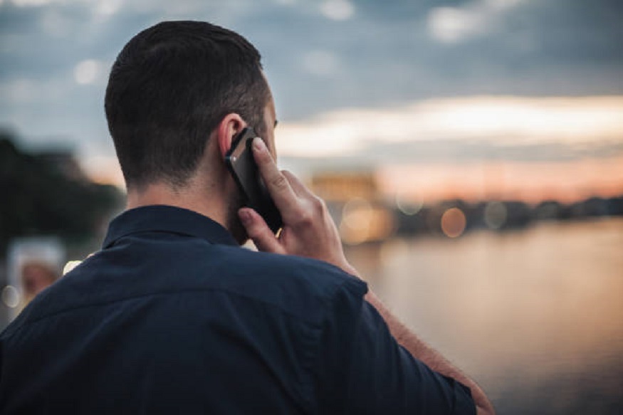 Businessman talking on mobile phone at sunset looking at evening city