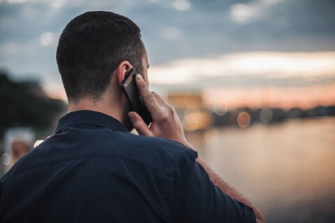 Businessman talking on mobile phone at sunset looking at evening city