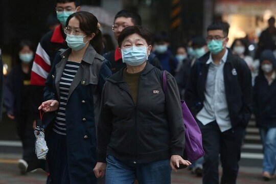 People wearing face masks to protect against the spread of the new coronavirus walks on a street in Taipei, Taiwan, Monday, March 30, 2020. The new coronavirus causes mild or moderate symptoms for most people, but for some, especially older adults and people with existing health problems, it can cause more severe illness or death. (AP Photo/Chiang Ying-ying)