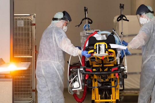 Medics take care of a patient infected with the novel coronavirus upon his arrival from Italy to the University hospital for further treatment in Dresden, Germany, Thursday March 26, 2020.  The new coronavirus causes mild or moderate symptoms for most people, but for some, especially older adults and people with existing health problems, it can cause more severe illness or death.(Matthias Rietschel/Pool via AP)