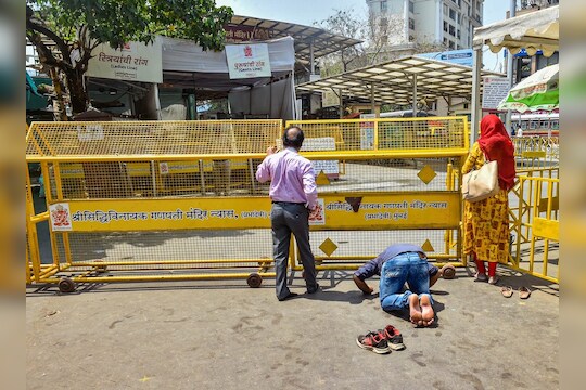 Mumbai: Devotees offer prayers behind the barricades set up on the entrance of Siddhivinayak Temple after it was closed for public as a measure to prevent the coronavirus pandemic, in Mumbai, Tuesday, March 17, 2020. (PTI Photo/Mitesh Bhuvad)(PTI17-03-2020_000121B)