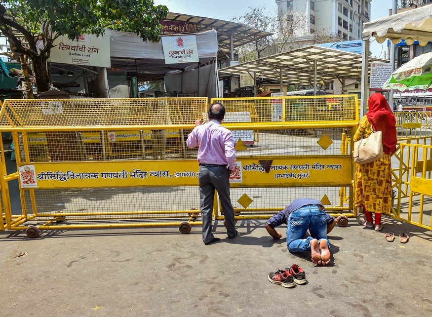 Mumbai: Devotees offer prayers behind the barricades set up on the entrance of Siddhivinayak Temple after it was closed for public as a measure to prevent the coronavirus pandemic, in Mumbai, Tuesday, March 17, 2020. (PTI Photo/Mitesh Bhuvad)(PTI17-03-2020_000121B)