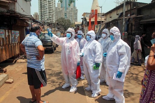 Mumbai: Doctors wearing protective suits check residents with an electronic thermometer inside a slum in Worli during the nationwide lockdown to curb the spread of coronavirus in Mumbai, Friday, April 17, 2020. (PTI Photo)
(PTI17-04-2020_000165B) *** Local Caption ***