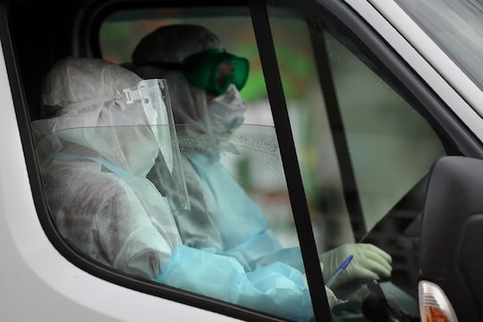 Medical employers in a protective suit sit inside an ambulance car near students dormitory in Minsk, Belarus, Tuesday, April 21, 2020. The World Health Organization is urging the government of Belarus to cancel public events and implement measures to ensure physical and social distancing amid the growing coronavirus outbreak. (AP Photo/Sergei Grits)