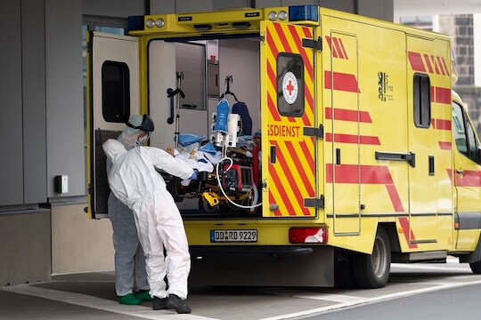 Medics take care of a patient infected with the novel coronavirus upon his arrival from Italy to the University hospital for further treatment in Dresden, Germany, Thursday March 26, 2020.  The new coronavirus causes mild or moderate symptoms for most people, but for some, especially older adults and people with existing health problems, it can cause more severe illness or death. (Matthias Rietschel/Pool via AP)