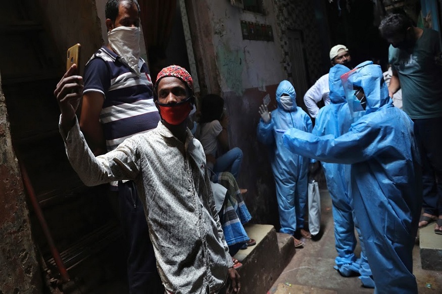 A man wearing mask takes selfie as health workers collect details of residents in Dharavi, one of Asia's largest slums, during lockdown to prevent the spread of the new coronavirus in Mumbai, India, Monday, April 13, 2020. The new coronavirus causes mild or moderate symptoms for most people, but for some, especially older adults and people with existing health problems, it can cause more severe illness or death. (AP Photo/Rafiq Maqbool)