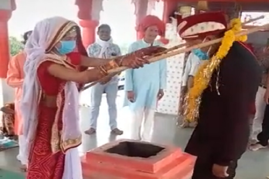 'सोशल डिस्टन्स' ठेवत पार पडलेल्या लग्नाचा VIDEO व्हायरल, काठी वापरून एकमेकांना घातली 'वरमाला'