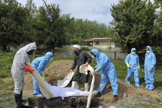 People wearing protective clothing attend the funeral of a victim who died from the new coronavirus, at a cemetery in the outskirts of the city of Ghaemshahr in north of Iran, Friday, May 1, 2020. (AP Photo/Ebrahim Noroozi)