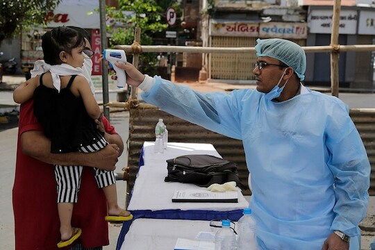 An Indian health worker checks the temperature of a child during lockdown to prevent the spread of new coronavirus in Ahmedabad, India, Wednesday, April 8, 2020. The new coronavirus causes mild or moderate symptoms for most people, but for some, especially older adults and people with existing health problems, it can cause more severe illness or death. (AP Photo/Ajit Solanki)