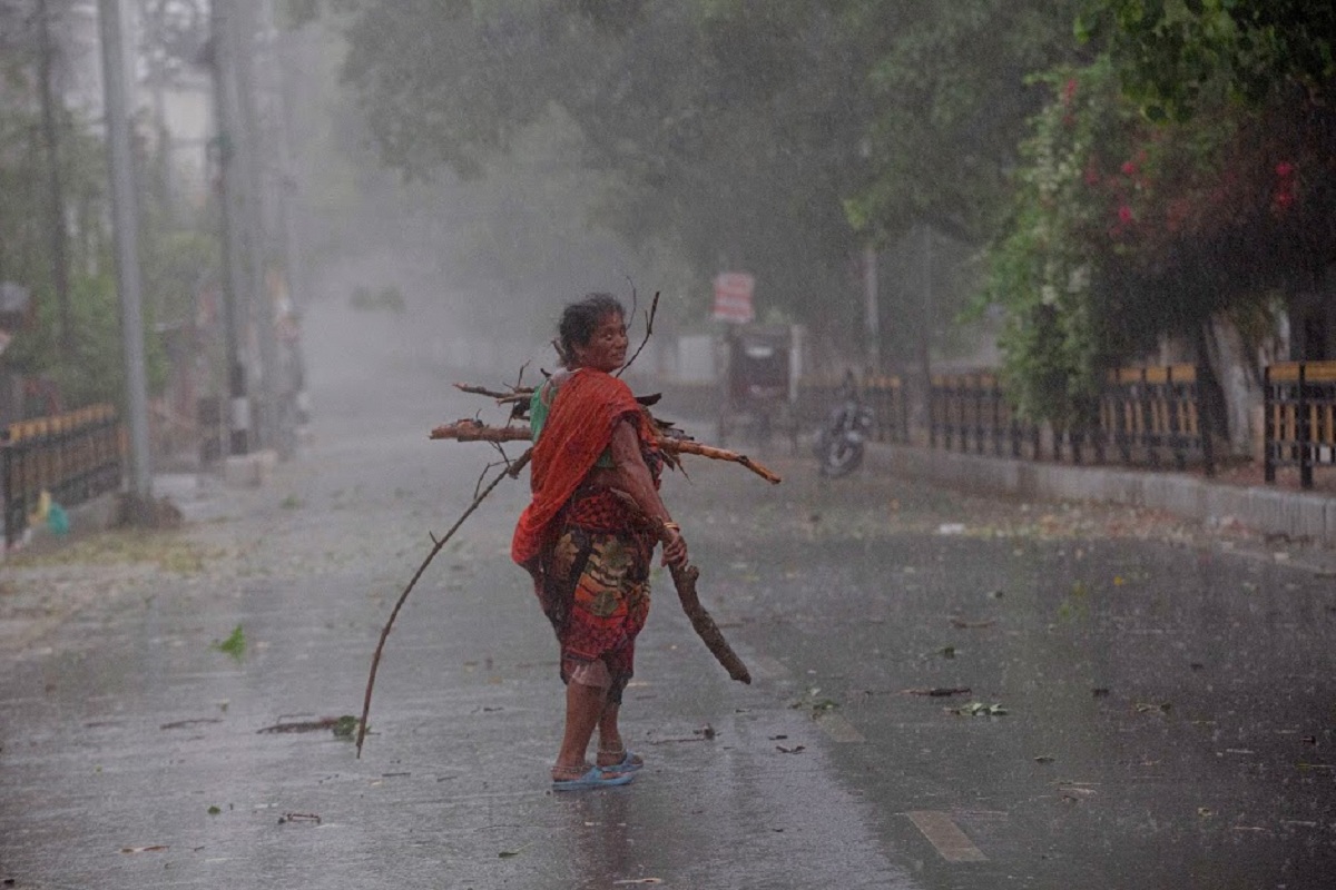 An Indian woman collects tree branches fallen on a road after a heavy downpour during lockdown in Gauhati, India, Wednesday, April 15, 2020. Indian Prime Minister Narendra Modi on Tuesday extended the world's largest coronavirus lockdown to head off the epidemic's peak, with officials racing to make up for lost time. (AP Photo/Anupam Nath)