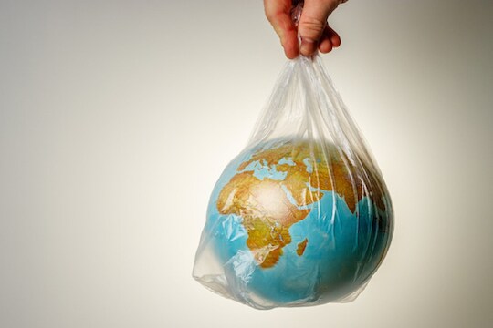 The concept of World Environment Day. The man's hand holds the earth in a plastic bag. In the blank for social advertising there is a place for the inscription.