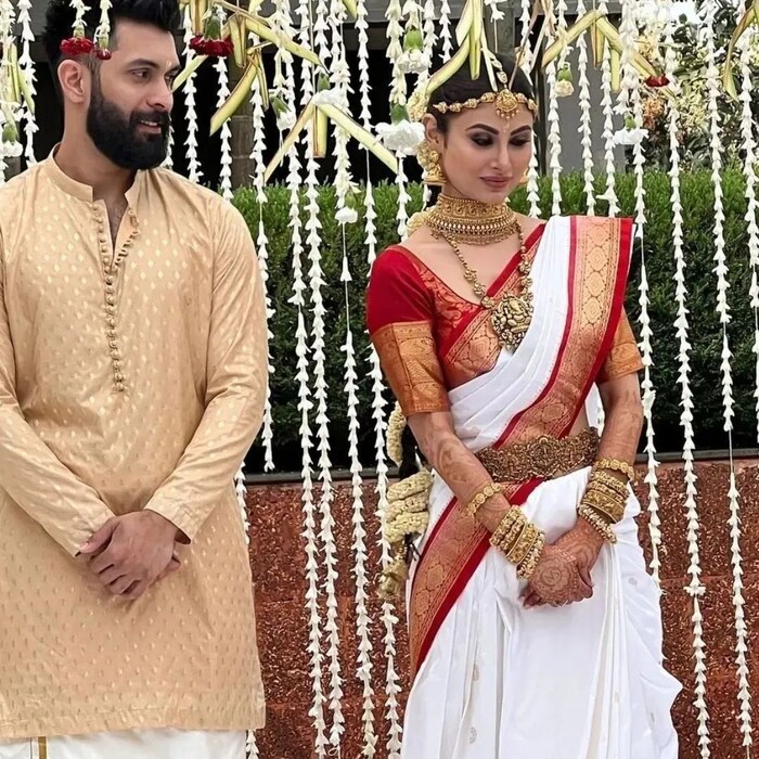 मौनीने आपल्या लग्नात पांढऱ्या रंगाची आणि लाल काठ असणारी साडी नेसली आहे. मौनी रॉय पारंपरिक दागिन्यांनी नटली आहे. या मल्याळम लुकमध्ये अभिनेत्रीचं सौंदर्य अजून खुलून दिसत आहे. 
