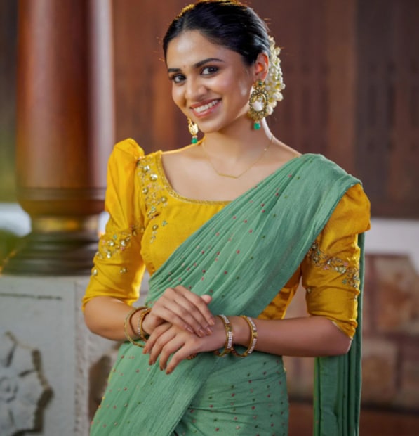  മസ്റ്റഡ് യെല്ലോ ജാക്കറ്റ്, ഇളം പച്ചനിറത്തിലെ ദാവണി, ഐവറി നിറത്തിലെ ലോങ്ങ് സ്കർട്ടുമാണ് മീനാക്ഷിയുടെ വേഷം. തലമുടി ബൺ രൂപത്തിൽ കെട്ടി, പൂക്കളാൽ അലങ്കരിച്ചിരിക്കുന്നു. കാതിൽ ഒരു സ്റ്റേറ്റ്മെന്റ് കമ്മലും കാണാം. സെലിബ്രിറ്റി മേക്കപ്പ് ആർട്ടിസ്റ്റായ ഉണ്ണി പി.എസ്. ആണ് മീനാക്ഷിയെ സുന്ദരിയായി ഒരുക്കിയത്. ചേച്ചിയുടേതിനു സമാനമായ പാവാടയും ബ്ലൗസുമാണ് മാമ്മാട്ടിയും അണിഞ്ഞിരിക്കുന്നത്.