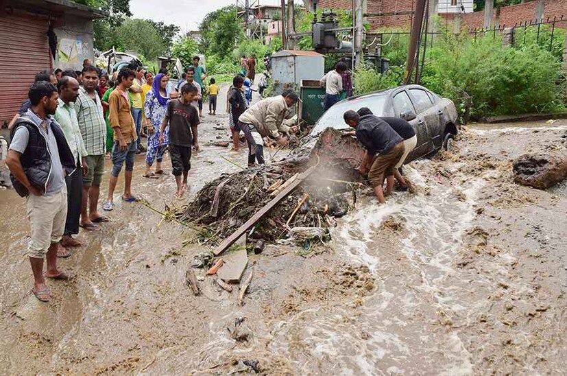  വെള്ളപ്പൊക്കത്തെ തുടർന്ന് അവശിഷ്ടങ്ങൾക്കിടയിൽപ്പെട്ട വാഹനത്തെ നീക്കുന്നു(ചിത്രം-പിടിഐ)