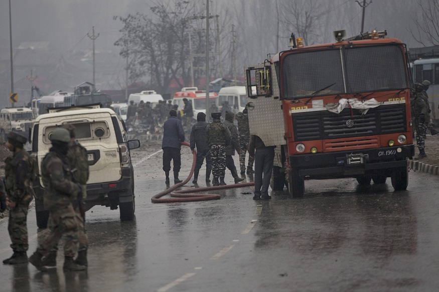 Indian firemen spray water on a road to wash away blood after an explosion in Pampore, Indian-controlled Kashmir, Thursday, Feb. 14, 2019. Security officials say at least 10 soldiers have been killed and 20 others wounded by a large explosion that struck a paramilitary convoy on a key highway on the outskirts of the disputed region's main city of Srinagar. (AP Photo/Dar Yasin)