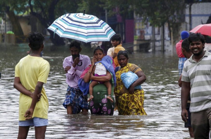  വെള്ളം നിറഞ്ഞ നിരത്തിലൂടെ കുട്ടിയുമായി നടന്നുനീങ്ങുന്ന കുടുംബം. (Image: AP)