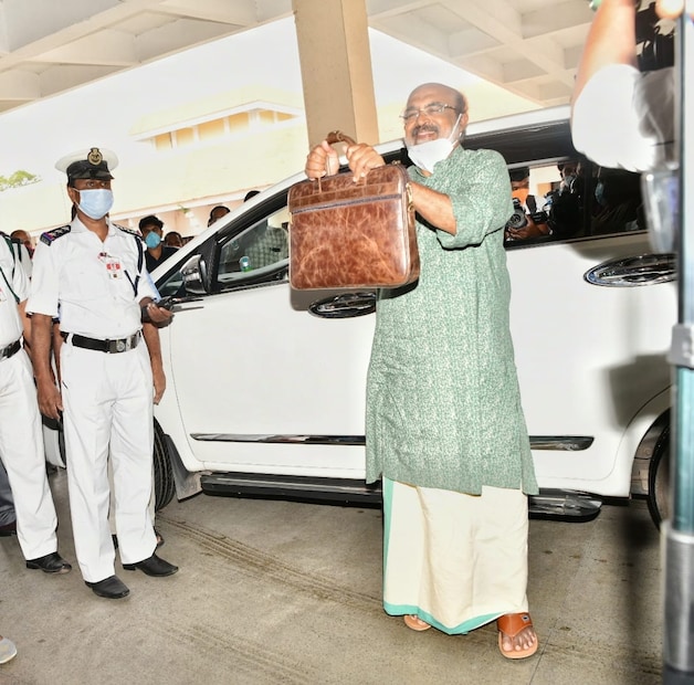  നിയമസഭയിൽ കാത്തുനിന്ന ഫോട്ടോഗ്രാഫർക്ക് മുന്നിൽ ബജറ്റ് അടങ്ങിയ ബാഗ് ഉയർത്തിക്കാട്ടുന്നു.