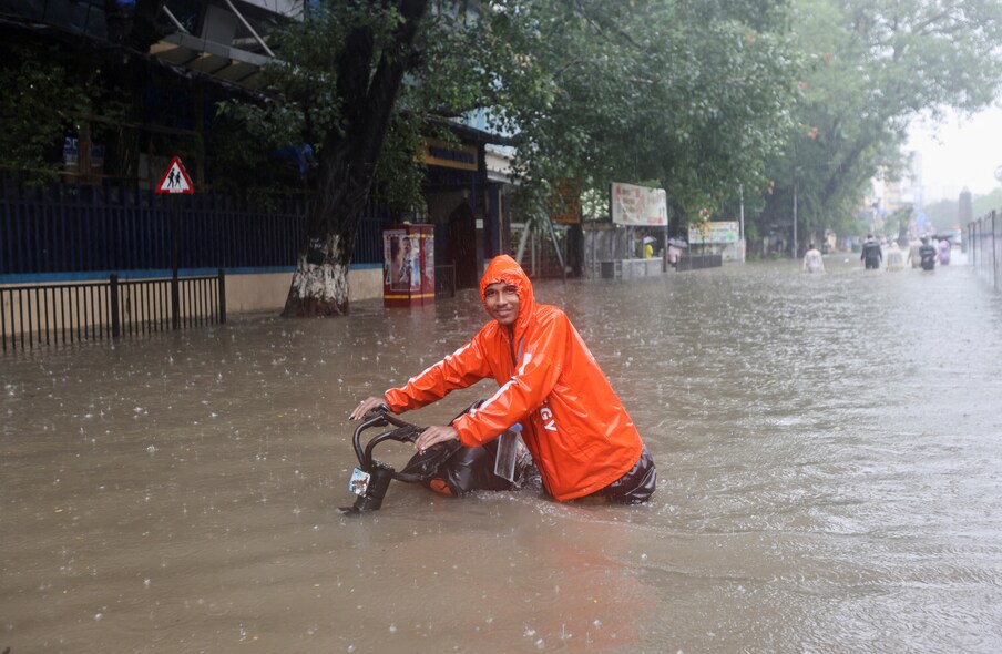 മഴയ്ക്കിടയിൽ വെള്ളക്കെട്ടിലൂടെ സൈക്കിളുമായി ഏന്തിവലിഞ്ഞു നടക്കുന്ന യാത്രികൻ India, July 5, 2022. REUTERS/Francis Mascarenhas - RC2L5V96JSUI