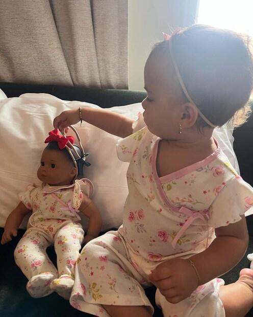  ഒരു പാവയ്‌ക്കൊപ്പം കളിക്കുന്ന കുഞ്ഞിന്റെ ചിത്രത്തിൽ അവളുടെ അതേ വസ്ത്രങ്ങളാണ് പാവയും അണിഞ്ഞിരിക്കുന്നത്.