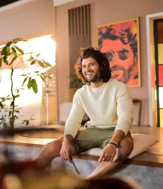 ബാൽക്കണി: റിലാക്സ് ചെയ്യാൻ വേറെന്തു വേണം? അതാണ് വിജയ് ദേവരകൊണ്ടയുടെ വീട്ടിലെ ബാൽക്കണി നൽകുന്ന വൈബ്. വീടിന്റെ ഈ ഭാഗത്തായി സമയം ചിലവിടാൻ ആഗ്രഹിക്കുന്ന വ്യക്തിയാണ് അദ്ദേഹം. ശുദ്ധവായുവും സൂര്യപ്രകാശവും ഇവിടെനിന്നും വേണ്ടുവോളം കിട്ടും. വീടിന്റെ മറ്റുഭാഗങ്ങളെന്ന പോലെത്തന്നെ ഇവിടെയും വെള്ളനിറത്തിന്റെ പ്രസരിപ്പ് തുടിക്കുന്നത് കാണാം. 'L' ഷേയ്പ് ഉള്ള ഒരു സോഫ ഇവിടെയിരുന്നുകൊണ്ട് സൗകര്യപ്രദമായി സമയം ചിലവിടാൻ സഹായകമാണ്. റസ്റ്റിക് ഓറഞ്ച് നിറത്തിലെ ഒരു ത്രോ പില്ലോ ഇതിനു മുകളിൽ കാണാം