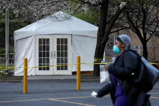 A health worker walks past a tent set up to screen people for coronavirus. (Reuters) A health worker walks past a tent set up to screen people for coronavirus. (Reuters)