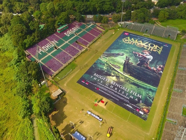 Amazon Obhijaan poster launched today. The film releasing on 22nd December. Scalling at a whopping 60,800 sq.ft ( 5640 sq.meters) The Amazon Obhijaan poster unveiled at Mohun Bagan ground on Saturday. This gigantic poster comfortably breaks the film poster record set by Baahubali which was 51,600 sq ft ( 4794 sq.meters). A large crowd flocked to the football ground to see the massive poster of the film. Amazon Obhijaan film poster is 97 meter long (320 feet) and 58 meter wide (190 feet) if placed vertically would be taller than Big ben (96 meters) or Qutub Minar ( 73 meters). Amazon Obhijaan poster launched today. The film releasing on 22nd December. Scalling at a whopping 60,800 sq.ft ( 5640 sq.meters) The Amazon Obhijaan poster unveiled at Mohun Bagan ground on Saturday. This gigantic poster comfortably breaks the film poster record set by Baahubali which was 51,600 sq ft ( 4794 sq.meters). A large crowd flocked to the football ground to see the massive poster of the film. Amazon Obhijaan film poster is 97 meter long (320 feet) and 58 meter wide (190 feet) if placed vertically would be taller than Big ben (96 meters) or Qutub Minar ( 73 meters).