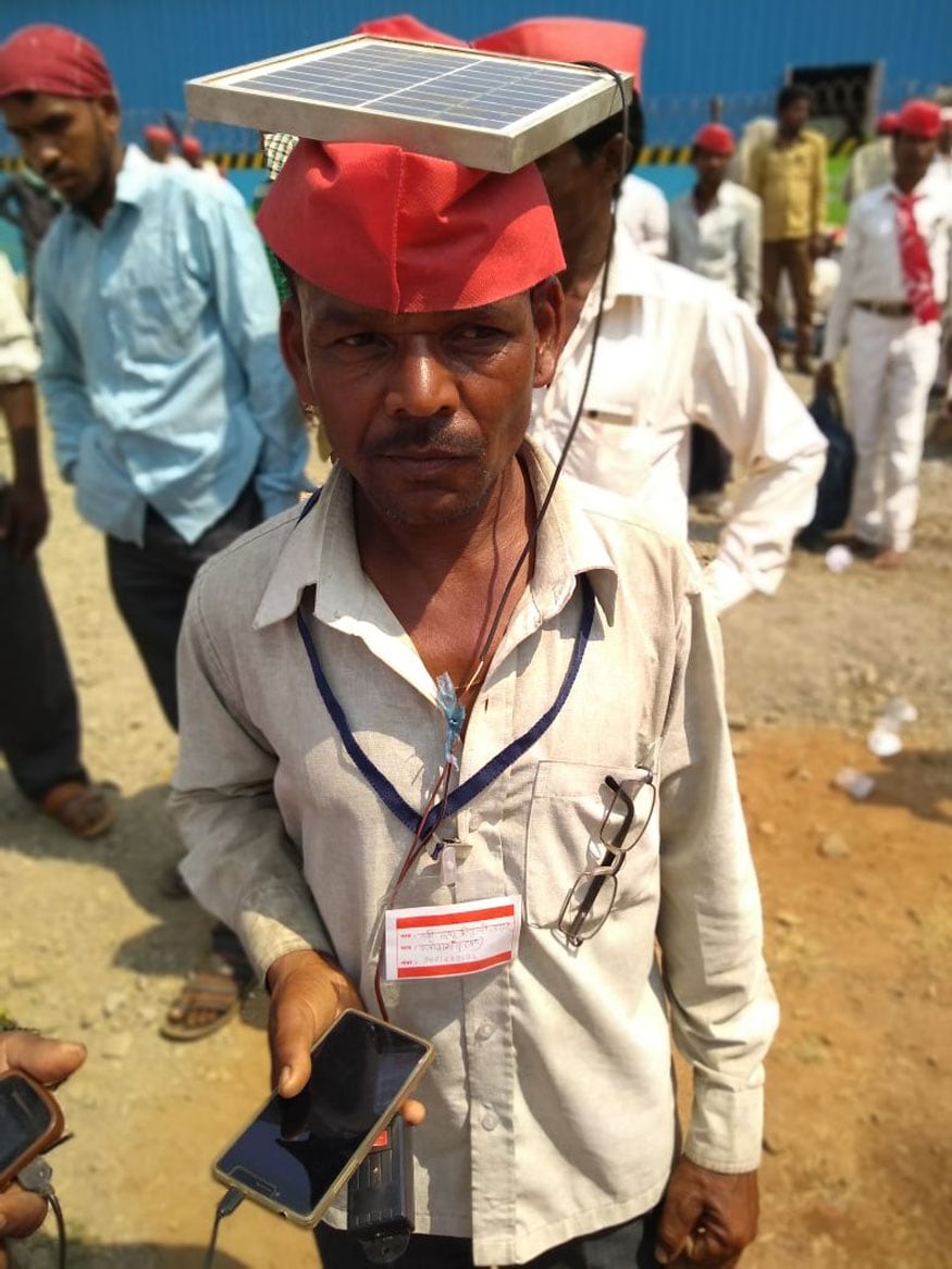 মাথু উদর, তার মাথায় সৌর প্যানেল স্থাপন করে কৃষকদের ফোন বিনামূল্যে চার্জ করে দিছেন। (Photo: Manish Dubey/News 18) মাথু উদর, তার মাথায় সৌর প্যানেল স্থাপন করে কৃষকদের ফোন বিনামূল্যে চার্জ করে দিছেন। (Photo: Manish Dubey/News 18)
