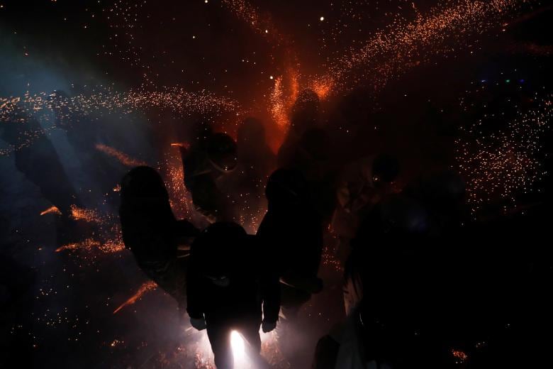 Participants wearing motorcycle helmets get sprayed with firecrackers, during the 'Beehive Firecrackers' festival at the Yanshui district in Tainan, Taiwan. (Image: REUTERS) Participants wearing motorcycle helmets get sprayed with firecrackers, during the 'Beehive Firecrackers' festival at the Yanshui district in Tainan, Taiwan. (Image: REUTERS)