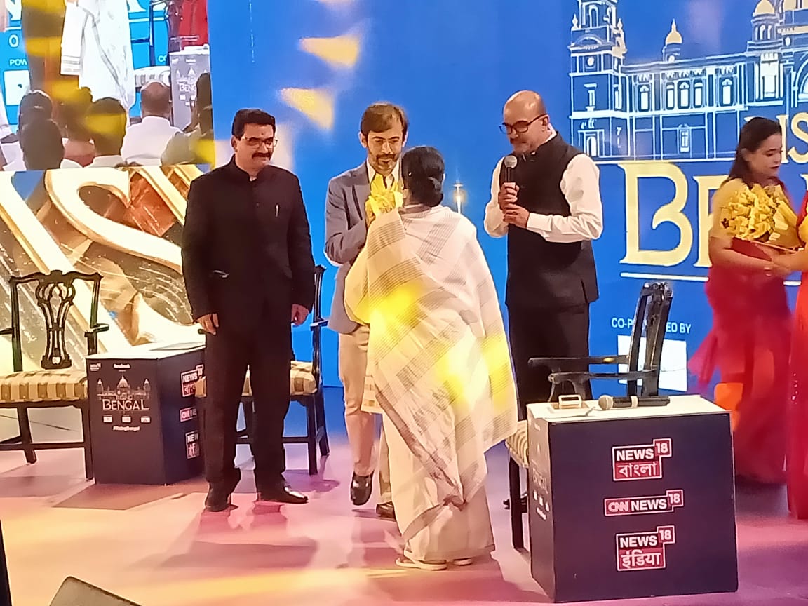 অনুষ্ঠানের মঞ্চে মুখ্যমন্ত্রী মমতা বন্দ্যোপাধ্যায়৷ উত্তরীয় পরিয়ে বরণ করলেন নিউজ 18 গ্রুপ এডিটর রাজেশ রায়না ৷ পুষ্প স্তবকে বরণ করলেন রাহুল যোশী ৷ (Photo: News18 Bengali) অনুষ্ঠানের মঞ্চে মুখ্যমন্ত্রী মমতা বন্দ্যোপাধ্যায়৷ উত্তরীয় পরিয়ে বরণ করলেন নিউজ 18 গ্রুপ এডিটর রাজেশ রায়না ৷ পুষ্প স্তবকে বরণ করলেন রাহুল যোশী ৷ (Photo: News18 Bengali)