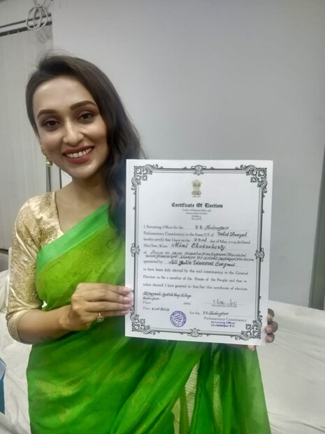 সবুজ শাড়ি পরে শংসাপত্র হাত মিমি চক্রবর্তী 