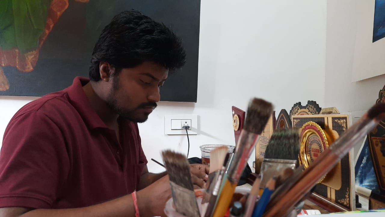 ছোটো প্রতিমার দিকেই ঝুঁকে পুজো উদ্যোক্তারা। সেদিকে তাকিয়ে তরুণ শিল্পীর এই ভাবনা। খুব ছোটো থেকেই আঁকার প্রতি তাঁর ঝোঁক। নিজের শহরকে ফুটিয়ে তুলেছেন তুলির টানে তো বটেই, আরো বহু ছবি এঁকেছেন তিনি। যা জায়গা পেয়েছে দেশ এবং বিদেশের একাধীক ম্যাগাজিনে। পেয়েছেন দেশ-বিদেশের প্রচুর সম্মান। ফ্রান্স, বাংলাদেশে তাঁর আঁকা ছবি জায়গা পেয়েছে। এবারে আর বড় ক্যানভাসে নয়, বেছে নিয়েছেন ছোট্ট একটা টিপকে। আর তাতেই মায়ের মৃন্ময়ী রূপ ফুটিয়ে তুলেছেন অবিকল। ছোটো প্রতিমার দিকেই ঝুঁকে পুজো উদ্যোক্তারা। সেদিকে তাকিয়ে তরুণ শিল্পীর এই ভাবনা। খুব ছোটো থেকেই আঁকার প্রতি তাঁর ঝোঁক। নিজের শহরকে ফুটিয়ে তুলেছেন তুলির টানে তো বটেই, আরো বহু ছবি এঁকেছেন তিনি। যা জায়গা পেয়েছে দেশ এবং বিদেশের একাধীক ম্যাগাজিনে। পেয়েছেন দেশ-বিদেশের প্রচুর সম্মান। ফ্রান্স, বাংলাদেশে তাঁর আঁকা ছবি জায়গা পেয়েছে। এবারে আর বড় ক্যানভাসে নয়, বেছে নিয়েছেন ছোট্ট একটা টিপকে। আর তাতেই মায়ের মৃন্ময়ী রূপ ফুটিয়ে তুলেছেন অবিকল।