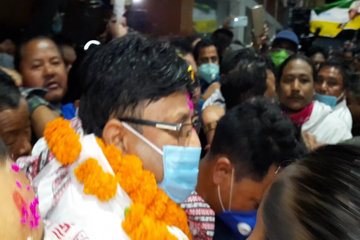 আজ বিমলের ছবি-সহ টি শার্ট পড়ে বিমানবন্দরে হাজির ছিলেন মোর্চা সমর্থকরা। সঙ্গে বিমলের ছবি লাগানো দলীয় ঝাণ্ডা। শয়ে শয়ে বিমলপন্থী মোর্চা সমর্থক পাহাড় থেকে নেমে আসেন সমতলে। ২০১৭ সালের জুনে পাহাড়ে বসেছিল রাজ্য মন্ত্রীসভার বৈঠক। ডাক পাননি বিমল গুরুং। ওইদিনই বিমলের নেতৃত্বে শুরু হয় আন্দোলন। পুলিশকে লক্ষ্য করে ছোড়া হয় ঢিল। পালটা পুলিশ লাঠি চালায়। মূহূর্তে শান্ত পাহাড় রণক্ষেত্র হয়ে ওঠে। একে একে আগুন ধরিয়ে দেওয়া হয় পুলিশের গাড়ি। পালটা কাদানে গ্যাসের শেল, গুলিও চালায় পুলিশ। টানা ১০০ দিনের বেশী পাহাড় বনধ চলে। এরই মধ্যে গা ঢাকা দেয় বিমল ও রোশন সহ তাঁদের ঘনিষ্ঠরা। আজ বিমলের ছবি-সহ টি শার্ট পড়ে বিমানবন্দরে হাজির ছিলেন মোর্চা সমর্থকরা। সঙ্গে বিমলের ছবি লাগানো দলীয় ঝাণ্ডা। শয়ে শয়ে বিমলপন্থী মোর্চা সমর্থক পাহাড় থেকে নেমে আসেন সমতলে। ২০১৭ সালের জুনে পাহাড়ে বসেছিল রাজ্য মন্ত্রীসভার বৈঠক। ডাক পাননি বিমল গুরুং। ওইদিনই বিমলের নেতৃত্বে শুরু হয় আন্দোলন। পুলিশকে লক্ষ্য করে ছোড়া হয় ঢিল। পালটা পুলিশ লাঠি চালায়। মূহূর্তে শান্ত পাহাড় রণক্ষেত্র হয়ে ওঠে। একে একে আগুন ধরিয়ে দেওয়া হয় পুলিশের গাড়ি। পালটা কাদানে গ্যাসের শেল, গুলিও চালায় পুলিশ। টানা ১০০ দিনের বেশী পাহাড় বনধ চলে। এরই মধ্যে গা ঢাকা দেয় বিমল ও রোশন সহ তাঁদের ঘনিষ্ঠরা।