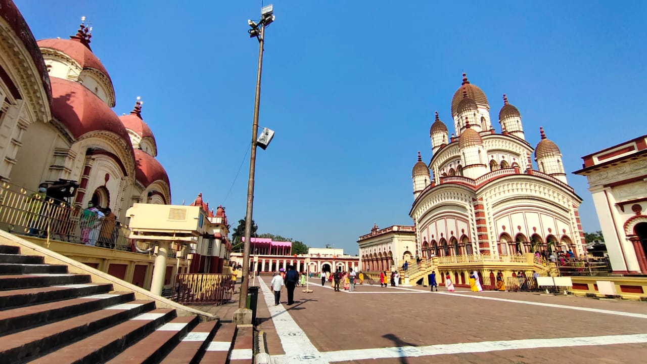 *তবে লোকাল ট্রেন চলাচল শুরু হয়ে যাওয়ার কারণে মানুষের উপস্থিতি ছিল সকাল থেকে চোখে পড়ার মতন। বেলা যত বাড়বে তত মানুষের ভিড় বাড়বে মন্দির চত্বরে। সকাল থেকেই অবশ্য শারীরিক দূরত্ব মেনেই লাইন রয়েছে মন্দিরে। এবার কোনও ভক্তকেই ফুল নিয়ে ভেতরে প্রবেশ করতে দেওয়া হচ্ছে না। মন্দিরের চাতালে মাস্ক পড়া বাধ্যতামূলক করা হয়েছে। সেদিকে নজর রাখা হচ্ছে। বাইরে ডালা আর্কেড ও পঞ্চবটী চত্বরেও ভিড় করতে দেওয়া হচ্ছে না। নজরদারি রয়েছে স্কাই ওয়াকেও। *তবে লোকাল ট্রেন চলাচল শুরু হয়ে যাওয়ার কারণে মানুষের উপস্থিতি ছিল সকাল থেকে চোখে পড়ার মতন। বেলা যত বাড়বে তত মানুষের ভিড় বাড়বে মন্দির চত্বরে। সকাল থেকেই অবশ্য শারীরিক দূরত্ব মেনেই লাইন রয়েছে মন্দিরে। এবার কোনও ভক্তকেই ফুল নিয়ে ভেতরে প্রবেশ করতে দেওয়া হচ্ছে না। মন্দিরের চাতালে মাস্ক পড়া বাধ্যতামূলক করা হয়েছে। সেদিকে নজর রাখা হচ্ছে। বাইরে ডালা আর্কেড ও পঞ্চবটী চত্বরেও ভিড় করতে দেওয়া হচ্ছে না। নজরদারি রয়েছে স্কাই ওয়াকেও।
