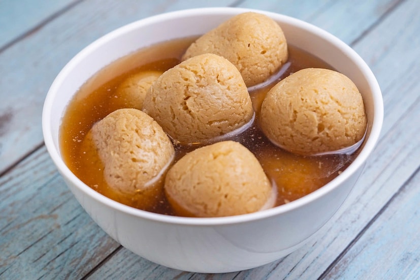 নলেন গুড়ের রসগোল্লা (Nolen Gur Roshogolla)- রসে টইটম্বুর, লালচে গোলাকার মিষ্টি মানেই শীতকালে বাঙালির কাছে নলেন গুড়ের রসগোল্লা (Nolen Gur Sweets)। সাদা রসগোল্লার থেকে এই সময়ে গুড়ের রসগোল্লাই বেশিরভাগ মানুষের ফেভারিট। এ ক্ষেত্রে রসগোল্লার রসে চিনির বদলে অল্প গুড় মেশানো হয়, রসগোল্লার মন্ডতেও গুড় মেশানো হয়ে থাকে। তাই মুখে দিলেই গলে যাওয়া আর সঙ্গে গুড়ের গন্ধ, যে কোনও মিষ্টিপ্রিয় মানুষ একসঙ্গে পাঁচ-ছ'টা খেয়ে নিতে পারে। আর যদি রসগোল্লা হয় গরম তা হলে তো কথাই নেই!
