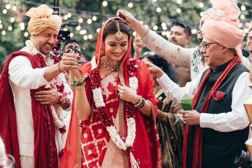 দেখা যাচ্ছে সোনালি জরির কাজ করা লাল বেনারসি শাড়ির সাজে নায়িকাকে, মাথায় বিয়ের সময়ে ছিল সোনালি কাজের লাল রেশমি ওড়না। সোনা আর মুক্তোর গয়নায়, খোঁপায় ফুলের সাজে একেবারে সাবেকি নববধূর রূপ ধরেছেন দিয়া। অন্য দিকে, বৈভব স্ত্রীর মতো বিশেষ সাজগোজের দিকে যাননি। তাঁর বিয়ের সাজ সম্পূর্ণ হয়েছে সাদা কুর্তা আর চুড়িদারে; মাথায় শোভা পেয়েছে সোনালি পাগড়ি।