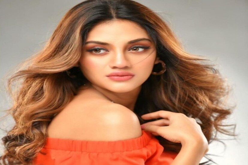 মা হওয়ার পর যেন কয়েকগুন বেড়েছে নুসরতের দীপ্তি। সেই আভা ঠিকরে বেরোচ্ছে আগুনে পোশাকের আড়ালেও। ক্যামেরার লেন্সে চোখ রেখে হাসছেন নুসরত। গোলাপি ঠোঁট, খোলা চুল, কাঁধ খোলা জামায় সেজেছেন তিনি।