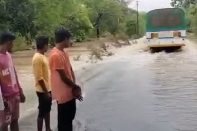 Locals watch as the driver tries to navigate the bus through a submerged bridge. (News18)
