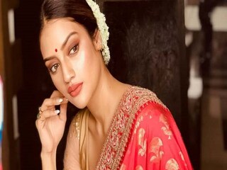 গাউন ড্রেপ
এ ধরনের শাড়ি পরার চল অবশ্য বাঙালির মধ্যে এখন নেই। কারসাজি মূলত আঁচলের। যেমন রোজের শাড়ি পরা হয়, তেমন করে পরে আঁচলটা একটু লম্বা রাখতে হবে। তারপর তাকে গলা দিয়ে ঘুরিয়ে সামনে এনে ফেলতে হবে ডান কাঁধের উপর থেকে। বুকের উপর দিয়ে এর আগে গিয়েছে শাড়ির যে অংশটা, তার ভিতরে ঢুকিয়ে ফেলতে হবে। এখানেও কিন্তু কোমরে একটা বেল্ট লাগবে। এ বার প্লিট গুলো ঠিক করে নিতে হবে। ঠিক মনে হবে যেন কোনও ভি-গলা গাউন পরা হয়েছে। তবে এ ক্ষেত্রে একটু নরম শাড়ি বাছাই ভাল।
