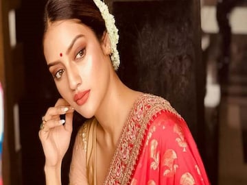 গাউন ড্রেপ
এ ধরনের শাড়ি পরার চল অবশ্য বাঙালির মধ্যে এখন নেই। কারসাজি মূলত আঁচলের। যেমন রোজের শাড়ি পরা হয়, তেমন করে পরে আঁচলটা একটু লম্বা রাখতে হবে। তারপর তাকে গলা দিয়ে ঘুরিয়ে সামনে এনে ফেলতে হবে ডান কাঁধের উপর থেকে। বুকের উপর দিয়ে এর আগে গিয়েছে শাড়ির যে অংশটা, তার ভিতরে ঢুকিয়ে ফেলতে হবে। এখানেও কিন্তু কোমরে একটা বেল্ট লাগবে। এ বার প্লিট গুলো ঠিক করে নিতে হবে। ঠিক মনে হবে যেন কোনও ভি-গলা গাউন পরা হয়েছে। তবে এ ক্ষেত্রে একটু নরম শাড়ি বাছাই ভাল।