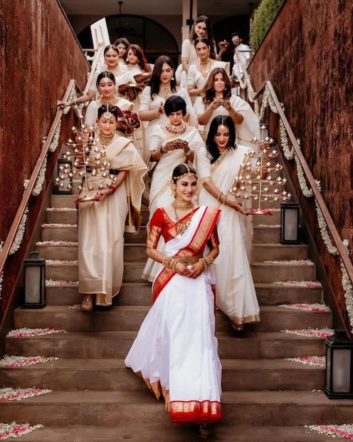 সাদা চাদোয়া এবং সাদা ফুল দিয়ে সাজানো হয়েছিল বিয়ের মণ্ডপ। লাল পাড় সাদা শাড়িতে সেজেছেন মৌনী। দক্ষিণী রীতিতে বিয়ে হলেও বেনারসি পরতে ভোলেননি কোচবিহারের মেয়ে