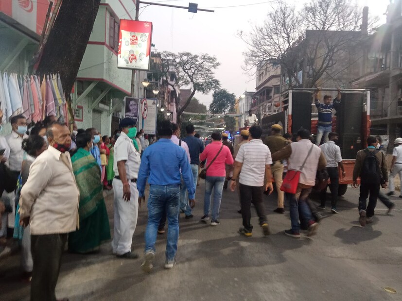রাস্তার দু'ধারে সন্ধ্যা মুখোপাধ্যায়ের ছবি সহ প্ল্যাকার্ড হাতে দাঁড়িয়ে বহু মানুষ। কোথাও কোনও রাজনৈতিক পতাকা নেই। 