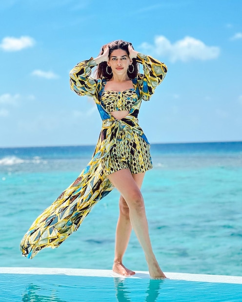স্বচ্ছ নীল জলের সামনে অ্যাসিমেট্রিক্যাল পোশাকে তিনি যেন এক ঝলক টাটকা বাতাস৷ 