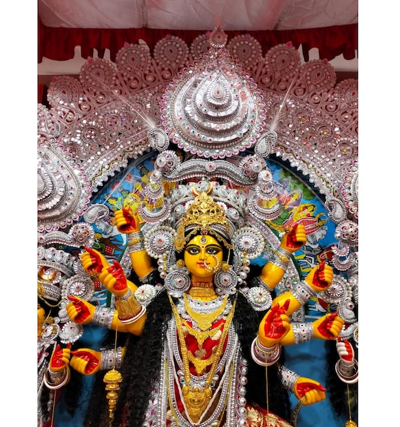 আর মায়ের সাঁজ? তাতে কি আলাদা থাকছেন? প্রশ্ন করলে ঋষি হেসে বলেন, 'দেবীর সাঁজ আমরা কি করে ঠিক করব বলতে পারেন? সে যেমন চায় নিজেকে সাজাতে তেমনই সাঁজে সাজবেন। তবে নাকের নথ, মাথায় মুকুট, চিক, সীতাহার, ঝাপটা, শাখা পলা বাঁধানো, তিকলি, টায়েরা, কানপাশা, লটকন, কোলাঙ্কি, মানতাসা সহ নানা গহনা। সঙ্গে পড়নে বেনারসি তো থাকছেই।' (Story & Image: Vaskar Chakraborty)