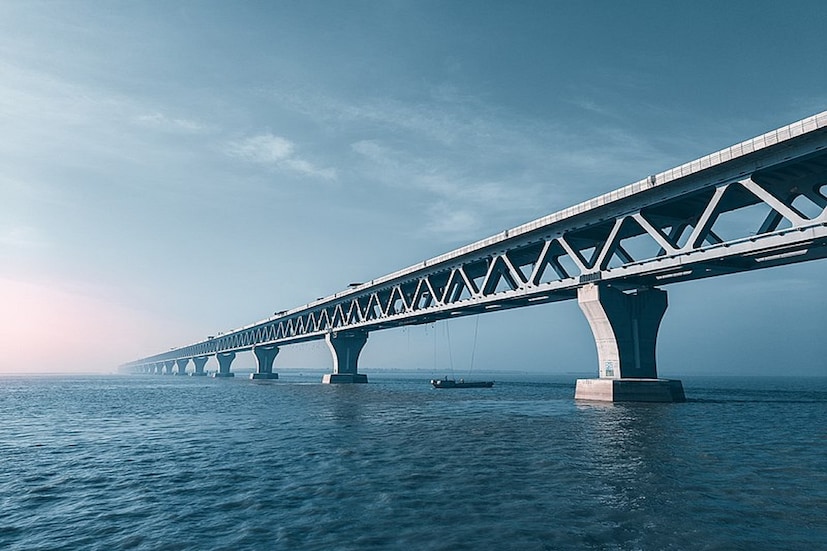 পদ্মা সেতু (Padma Setu)। বাংলাদেশের এই ইমারত এখন গোটা বিশ্বের চর্চায়। সেই সেতু উদ্বোধন হওয়ার পর থেকেই মানুষের মধ্যে কৌতূহলের শেষ নেই। বহু মানুষ এই পদ্মা সেতুর উপর দিয়ে পারাপারের জন্য মুখিয়ে রয়েছেন। এই পদ্মা সেতু বাংলাদেশের কাছে এখন ঐতিহ্য হয়ে দাঁড়িয়েছে।