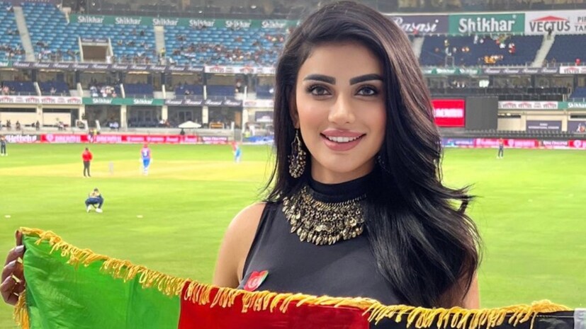 বিষয়টা ভেঙেই বলা যাক! দুবাইয়ে এশিয়া কাপ চলাকালীন স্টেডিয়ামে উপস্থিত এক তরুণীর ছবি ভাইরাল হয়। কাটা-কাটা চোখ-মুখ, কাঁধ-ছাপানো রেশমি কালো খোলা চুল, পরনে ম্যাজেন্টা-হলুদ ফ্লোরাল ম্যাক্সি ড্রেস এবং গলায় ভারী জাঙ্ক জুয়েলারি। হাতে তাঁর নিজের দেশ আফগানিস্তানের জাতীয় পতাকা এবং ঠোঁটে গর্বের এক চিলতে হাসি। এই ছবি ভাইরাল হতেই শুরু হয়ে যায় খোঁজ। অবশেষে জানা গিয়েছে সুন্দরী এই মহিলার পরিচয়। তাঁর নাম ওয়াজমা আয়ুবি (Wazhma Ayoubi)। বাংলাদেশ-আফগানিস্তান ম্যাচের দিন নিজের দেশ আফগানিস্তানের হয়ে গলা ফাটাতেই মাঠে এসেছিলেন তিনি। আর সেখান থেকেই ফ্যান ফলোয়িং বেড়েছে তাঁর নিজেরও। 