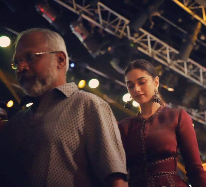 মণি রত্নমের সঙ্গে অভিনেত্রী, পরেছেন মেরুন লাল পোশাক ও বড় ঝুমকা। 