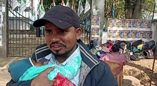 সন্তান কোলে নিয়ে পরীক্ষা কেন্দ্রের বাইরে অপেক্ষায় পরীক্ষার্থীর স্বামী।