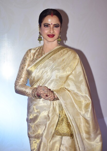 বলিউডের সেলিব্রিটি পার্টি হোক কিংবা অ্যাওয়ার্ড অনুষ্ঠান, রেখার উপস্থিতির সঙ্গে সঙ্গে সেখানে যেন চাঁদের হাট বসে। কাঞ্জিভরম শাড়ি, তার সঙ্গে ভারী গয়না, একমাথা সিঁদুর এবং সেই সঙ্গে মানানসই মেকআপ, রেখাকে দেখলে যেন চোখ ফেরানো যায় না। আজ পর্যন্ত কখনও তাকে শাড়ি ছাড়া দেখা যায়নি। আবার শাড়ির মধ্যে কাঞ্জিভরম তার প্রথম পছন্দ। কিন্তু কেন সবসময় এই একই ধরণের শাড়ি বেছে নেন বলিউড সুন্দরী?