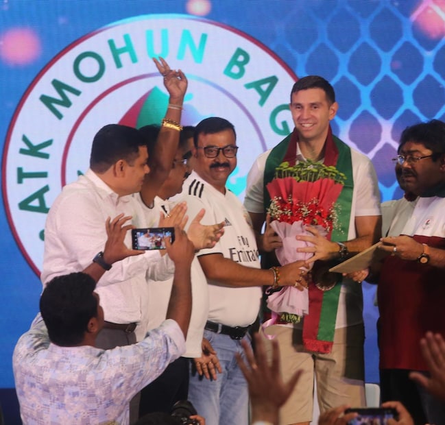 এমিকে সবুজ মেরুন উত্তরীয় এবং ফুলের স্তবক দিয়ে বরণ করে নেন মোহনবাগান কর্তারা